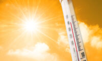 Thermometer against the background of an orange yellow hot glow of clouds and sun, concept of hot weather